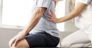 Modern rehabilitation physiotherapy worker with senior client; blog: Will I Need Physical Therapy After Back Surgery?